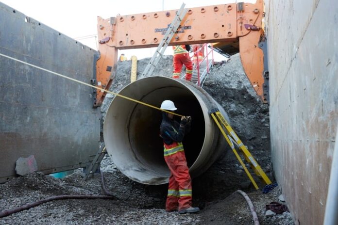 a man stands next to a large exposed pipe