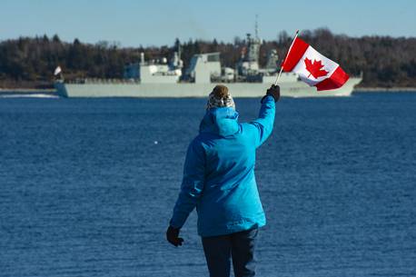 Mary MacAfee waves a Canadian flag as she watches HMCS Halifax leave on a six-month deployment as part of NATO's Operation Reassurance on Friday, January 1, 2021. MacAfee's son-in-law Petty Officer Phil Hudson is aboard the Halifax.