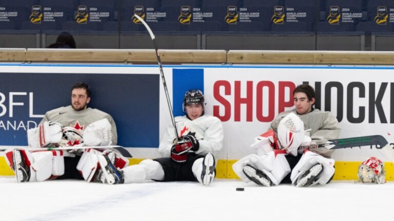 Canada's captain Fraser Minten(12) drops in between goaltenders Mathis Rousseau, left and Scott Ratzlaff following practice at the Scandinavium arena prior to the start of the IIHF World Junior Hockey Championship in Gothenburg, Sweden on Monday, Dec. 25, 2023. Canada will face Finland in their first game on December 26. THE CANADIAN PRESS/Christinne Muschi
