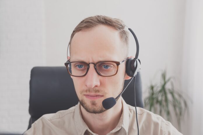Junger Mann, der Headset für Online -Kommunikation als virtuellen Kundenservice trägt