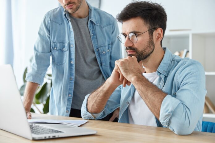 Business meeting concept. Cropped image of two businessmen discuss photo of diagram on laptop, work