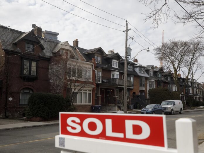 A for sale sign in front of homes in the Midtown neighborhood of Toronto, Ontario.