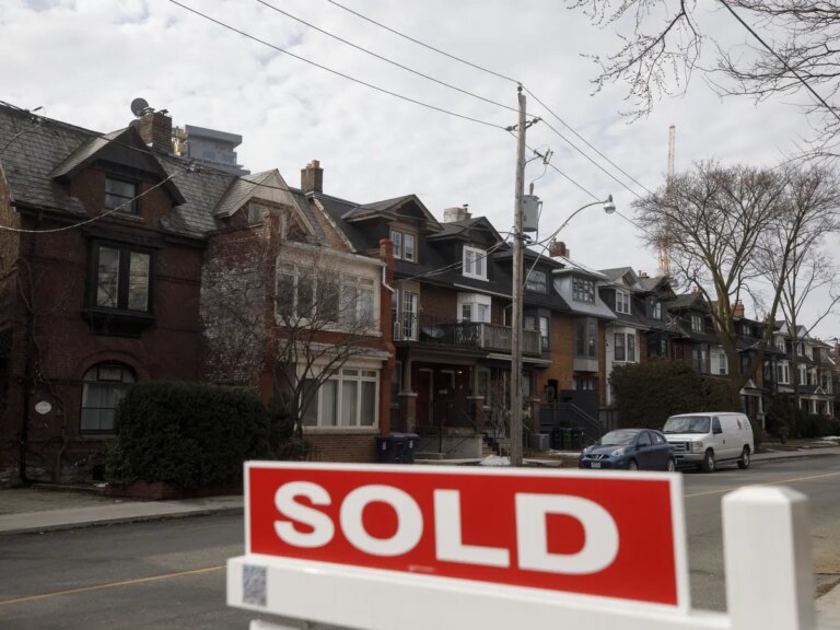 A for sale sign in front of homes in the Midtown neighborhood of Toronto, Ontario.